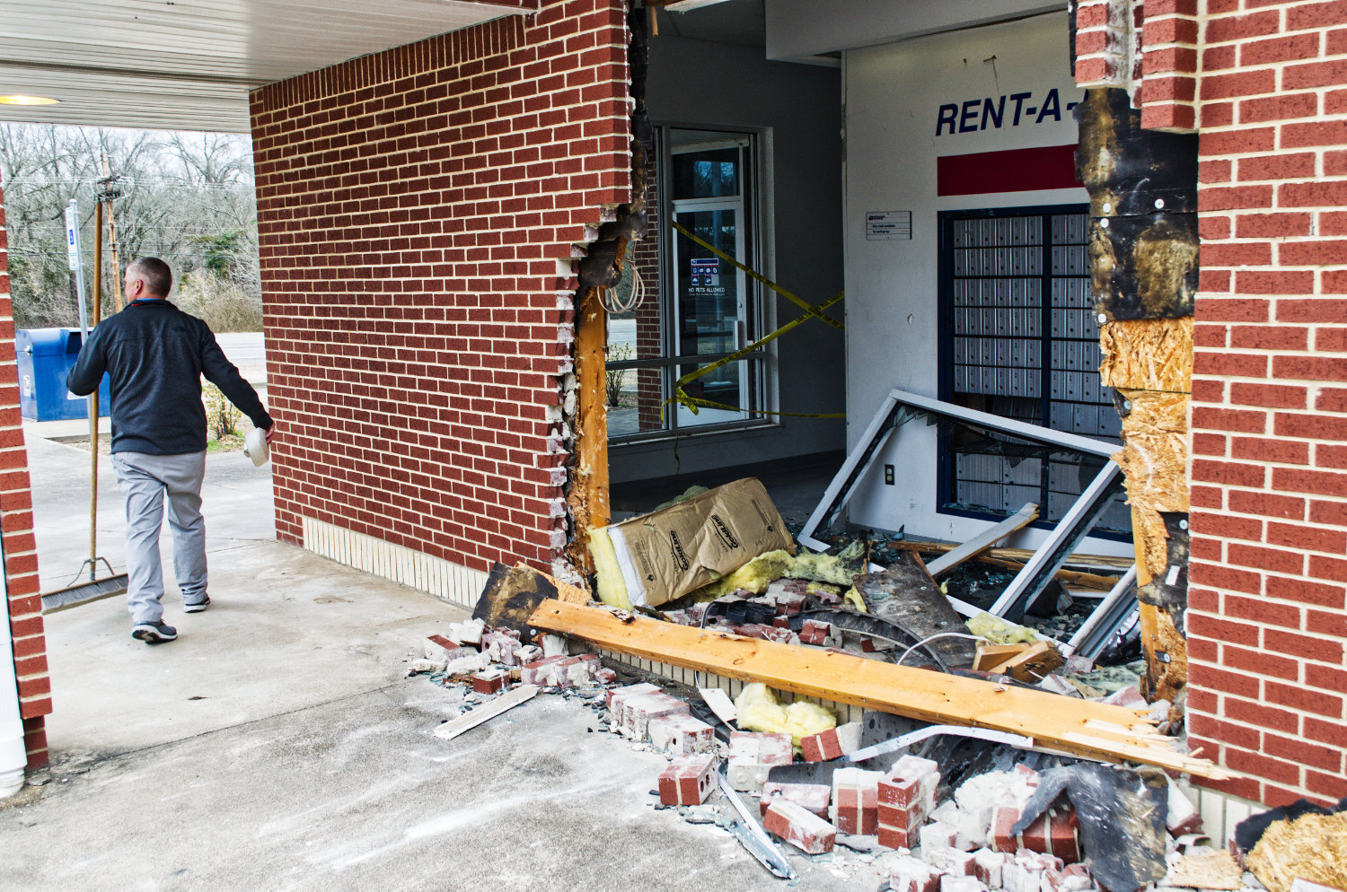 The exterior of the west side of the Post Office building in Mineola, with a hole just wider than the vehicle that smashed through the brick wall.